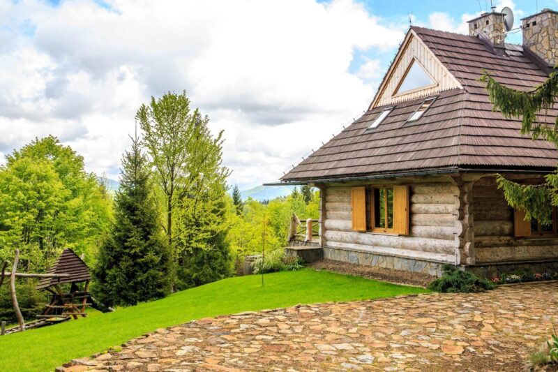 A house with a stone patio and trees in the background.
