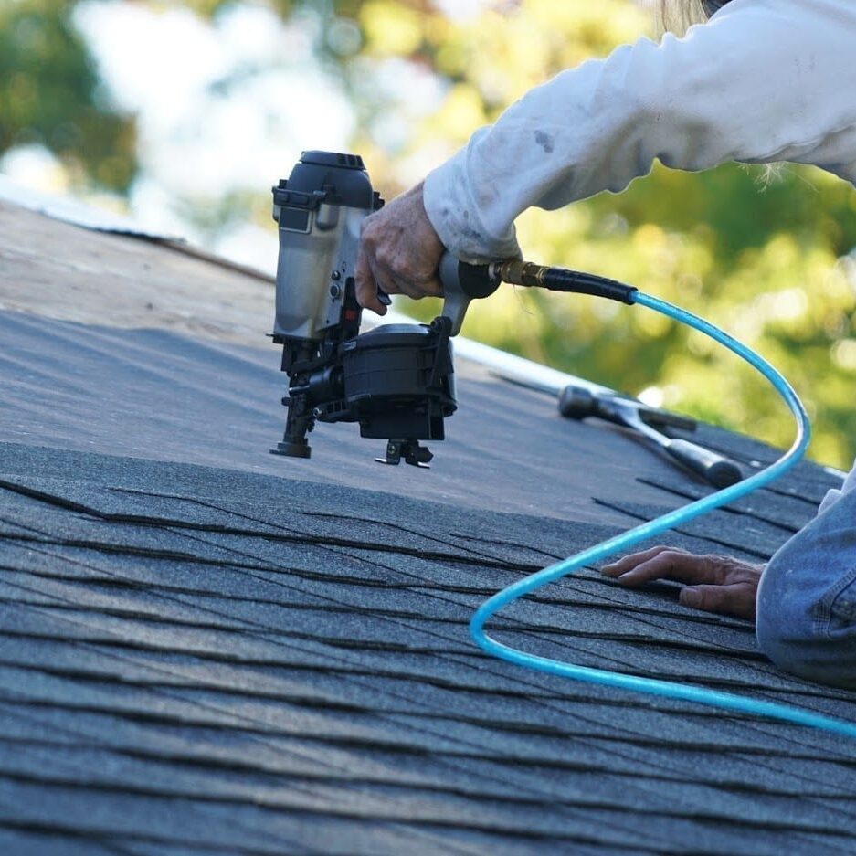 Contractor installing durable impact resistant shingles on a house roof.